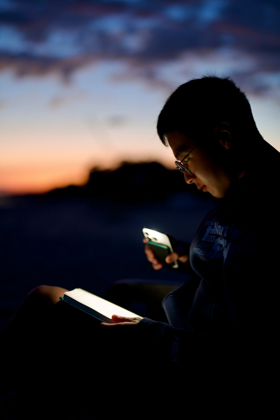 person reading book at dusk